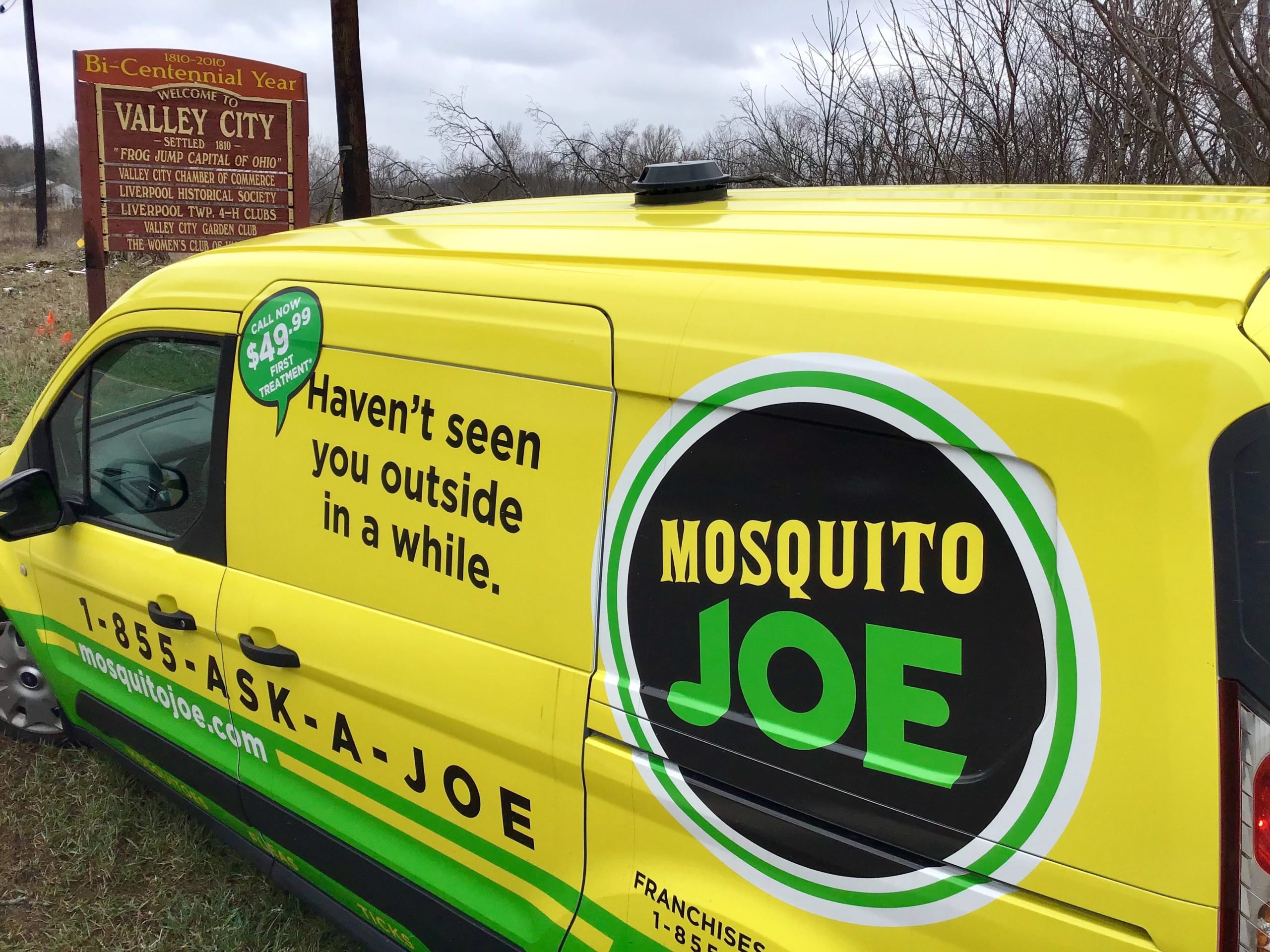 A yellow and green Mosquito Joe service vehicle is parked near a Valley City sign in Medina, Ohio.